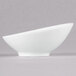 An Arcoroc Ludico porcelain bowl with a curved edge on a gray background.