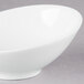 An Arcoroc white porcelain bowl with a small rim on a gray surface.