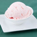 An Arcoroc Ludico porcelain bowl filled with pink ice cream and topped with a strawberry.