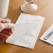 A person's hand holding a white Choice dinner napkin.