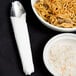 A bowl of noodles and rice next to a Hoffmaster white linen-like napkin on a table.