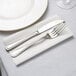 A fork and knife on a Hoffmaster white linen-like napkin.