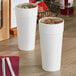 Two white Dart foam cups with ice on a table.