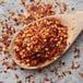 A wooden spoon filled with red and yellow Regal Crushed Red Pepper flakes.
