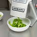 A Hobart food processor with a bowl of green peppers.