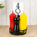 A black wrought iron condiment caddy with three red and yellow containers.