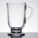 A Libbey clear glass coffee mug with a handle on a table.