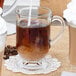 A Libbey Irish glass coffee mug filled with brown liquid with a straw in it.