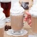 A hand holding a Libbey Irish glass coffee mug filled with whipped cream coffee.
