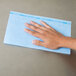 A person's hand using a blue Chicopee Chix foodservice towel.