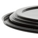 A stack of black WNA Comet round catering trays with lids.
