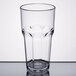 A close-up of a Carlisle clear plastic tumbler with a rim on a table.