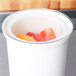 A clear Cambro lid on a white container with fruit inside.
