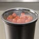 A black Cambro lid on a black container full of tomatoes.
