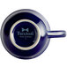 A cobalt blue Tuxton tea cup with white text on it.