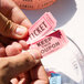 A pair of hands holding two pink Carnival King raffle tickets.