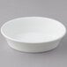 A Tuxton white oval china baker dish on a gray surface.