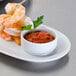 A stack of Arcoroc white porcelain bowls filled with shrimp and red sauce.