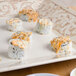 A square white melamine plate with sushi on a wood table.