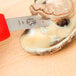 A Victorinox oyster knife with a red handle cutting an oyster.