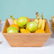 An American Metalcraft bamboo bowl filled with fruit on a table.