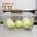 A Carlisle clear food storage container holding cabbages on a table.
