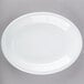 A Tuxton white oval china coupe platter on a gray surface.