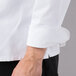 A close up of a Mercer Culinary white chef jacket sleeve with a cloth knot button.