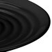 A close-up of a black GET Milano melamine plate with a wavy edge.