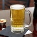 A Libbey beer mug filled with beer on a table with a napkin.