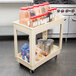 A Continental beige plastic utility cart with food items on it, including clear plastic containers with red lids.