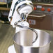 A white KitchenAid commercial stand mixer with a metal bowl and spiral dough hook in it.
