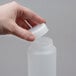 A hand opening a FIFO Innovations 12 oz. white plastic squeeze bottle with a lid.