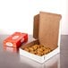 A white customizable pie box on a table with a box of cookies inside.