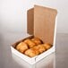 A white customizable bakery box filled with pastries on a table.