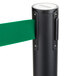 A black Aarco crowd control stanchion with green retractable tape.