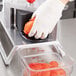 A person in gloves using a Vollrath Redco InstaSlice machine to cut tomatoes.
