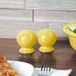 A yellow Fiesta salt shaker on a table with yellow bowls and a pizza.