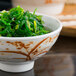 A Thunder Group round melamine bowl with a green design filled with seaweed salad.