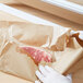 A person wrapping a piece of meat in Bagcraft Packaging natural freezer paper.