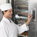 A woman in a chef's uniform using a Traulsen blast chiller touch screen.