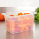 A translucent plastic Cambro food pan filled with peppers.