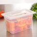 A translucent plastic food pan full of peppers with a lid.
