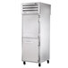 A large silver True pass-through refrigerator with solid front half doors and glass back full doors.