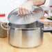 A chef using a Vollrath sauce pot with a metal handle.