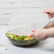 A person holding a Fineline smoke plastic bowl filled with salad.