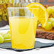 A clear Fineline plastic tumbler with orange juice and a slice of orange on the rim.