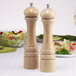 Two wooden Chef Specialties pepper mills on a table.