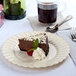 A slice of chocolate cake with a raspberry and mint leaf on a Fineline Flairware plastic plate.