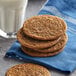 A stack of cookies on a blue napkin next to a glass of milk.